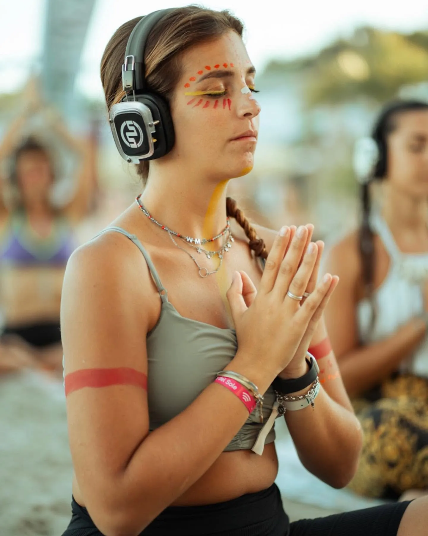Partecipante con il viso dipinto a mani giunte durante una sessione a un festival