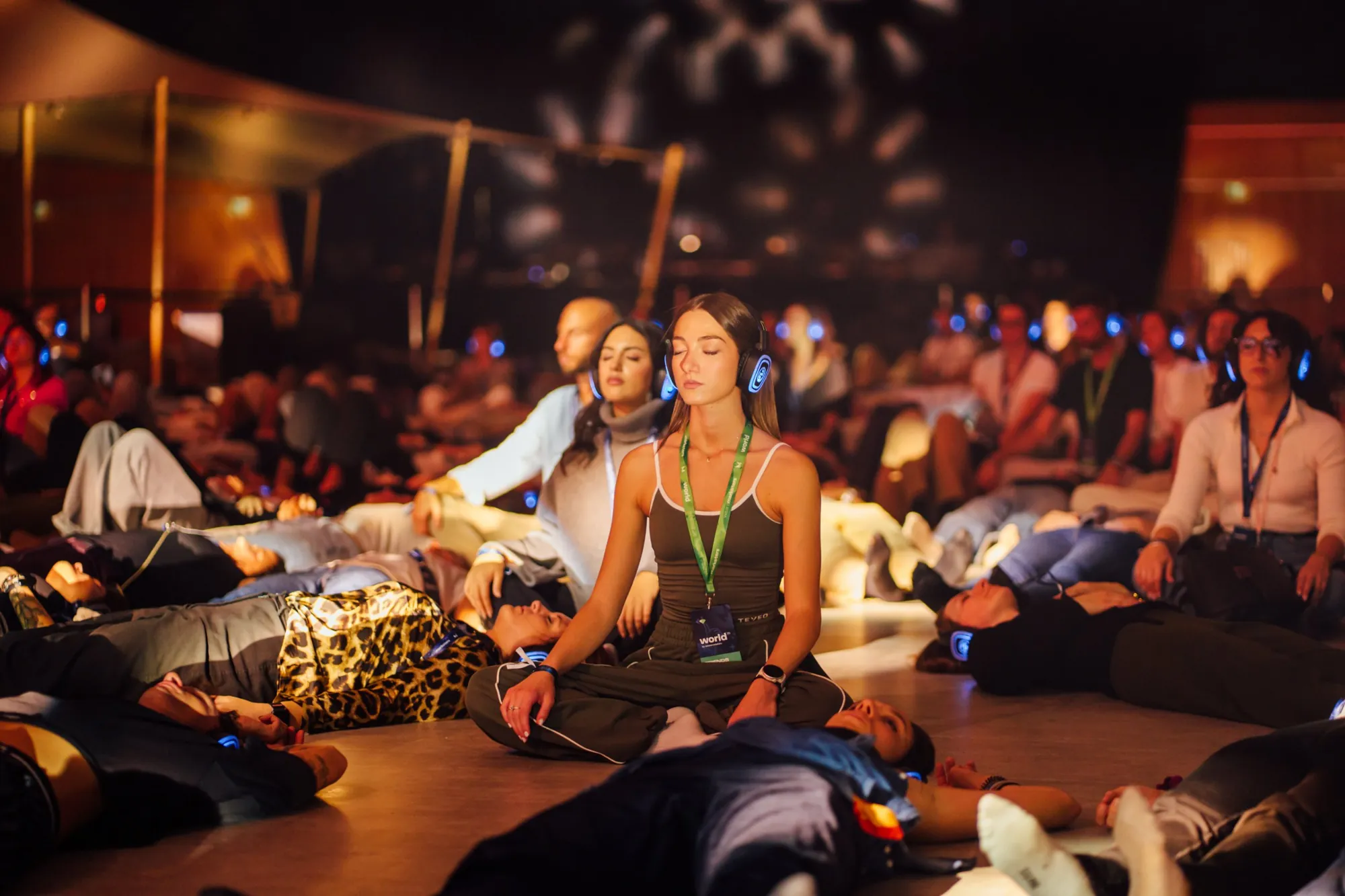 Meditazione di gruppo a un evento, con cuffie wireless dalle luci blu
