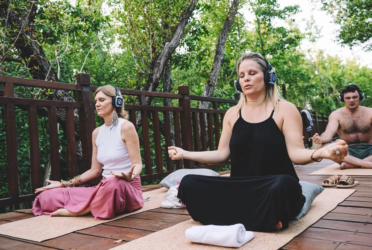 Meditazione su una pedana di legno tra gli alberi, con cuffie wireless